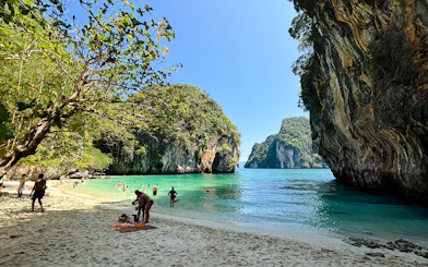 Tourists enjoying the beach and snorkeling at Hong Islands, Krabi, with limestone cliffs and clear water.