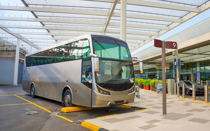 Public transport bus at a stop in Singapore under a modern canopy.