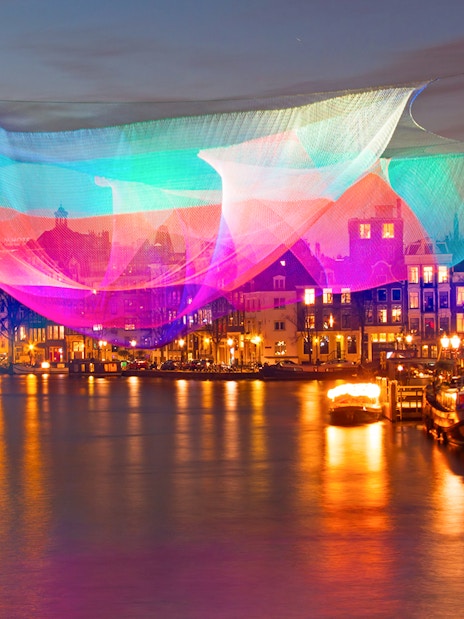 Colorful light installation over Amsterdam canal during Lights Festival.