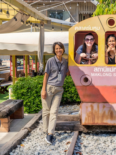 Visitors posing with a train cutout at Maeklong Railway Market station.