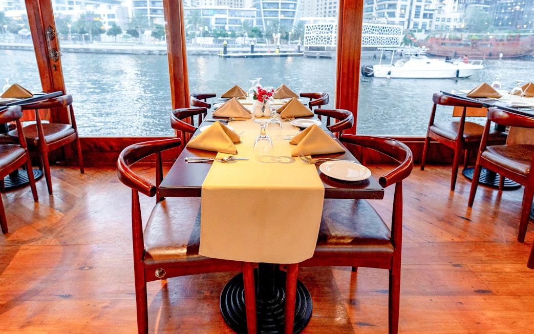 Elegant dining setup on a dhow cruise with waterfront view, part of the Sunset Alexandra VIP experience.