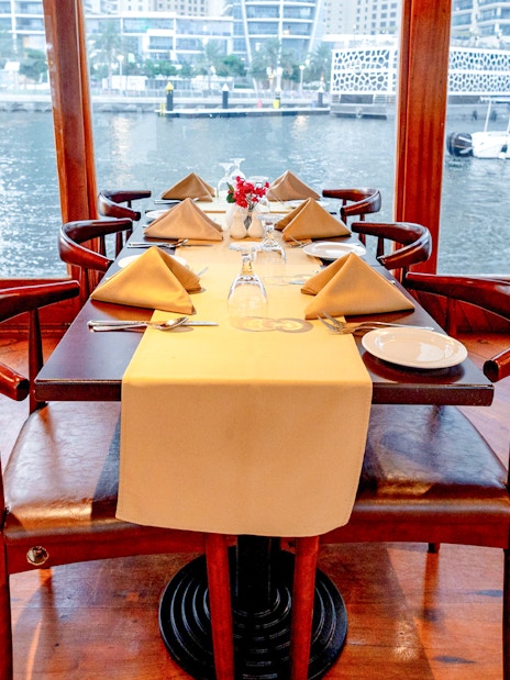 Elegant dining setup on a dhow cruise with waterfront view, part of the Sunset Alexandra VIP experience.