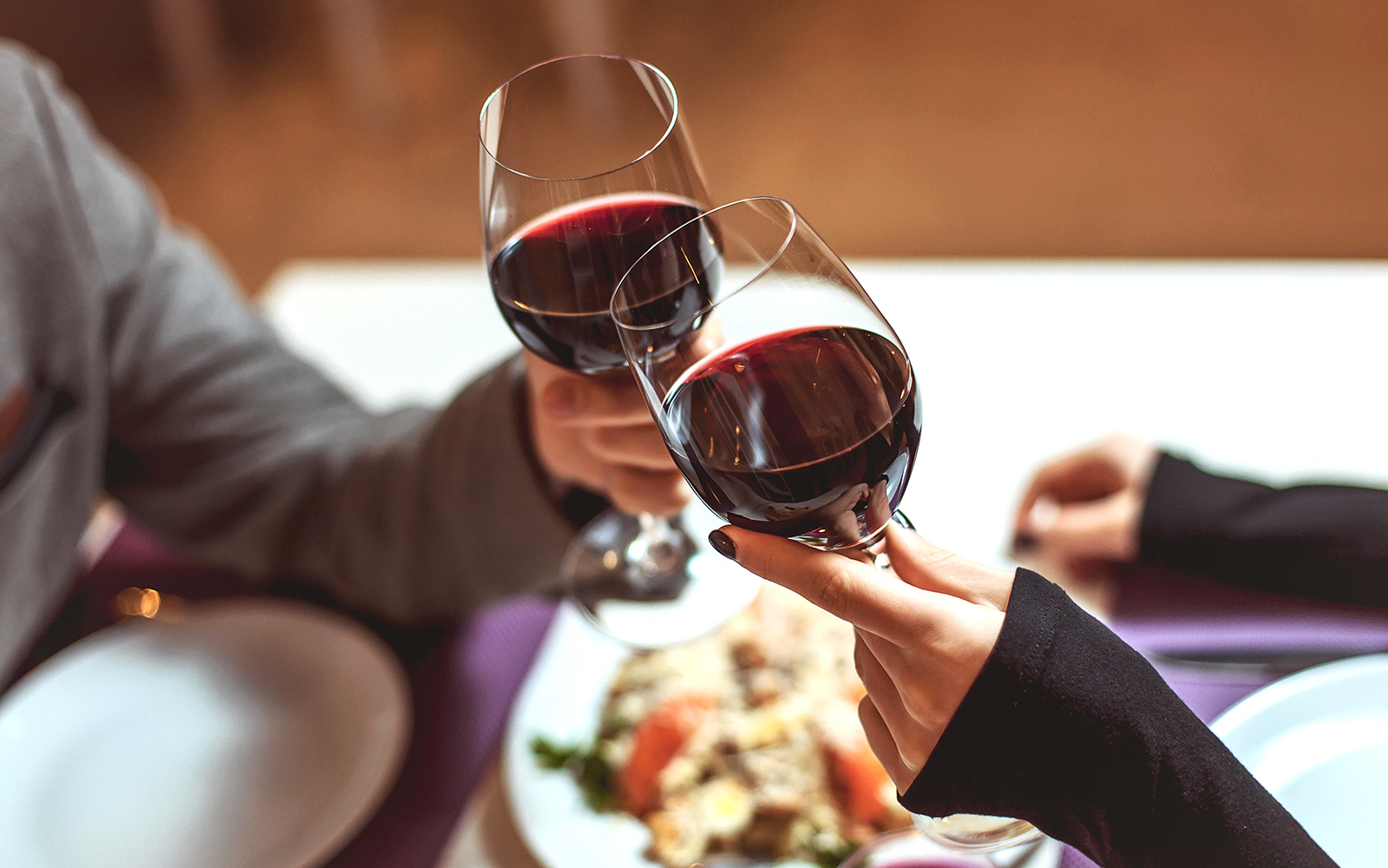 Guests toasting with red wine during a gourmet dinner in Tuscany.