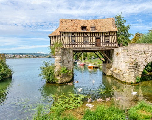 Old mill of Vernon with lush greenery, part of Paris to Giverny tour.
