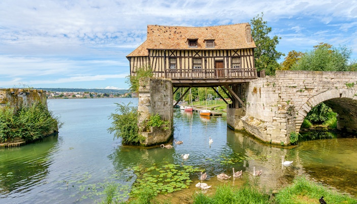 Old mill of Vernon with lush greenery, part of Paris to Giverny tour.