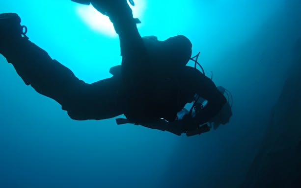 Certified diver exploring underwater in Aci Castello, Italy.