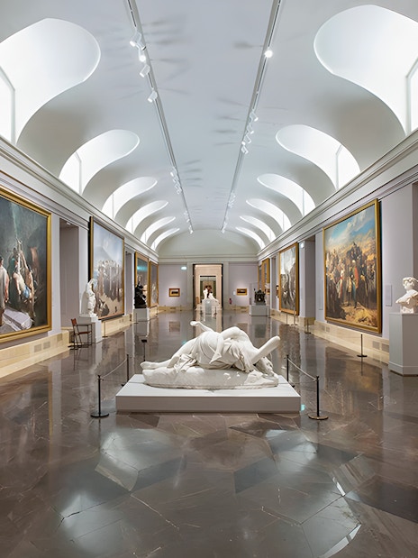 Prado Museum gallery with classical paintings and sculptures on display.