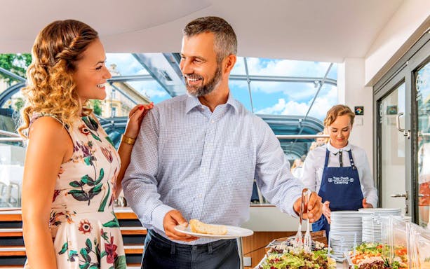 Couple enjoying buffet on Vltava River sightseeing cruise in Prague.