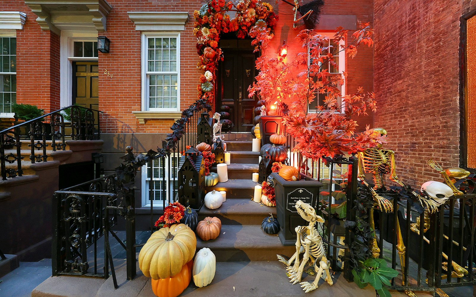 New York City brownstone with Halloween decorations, including pumpkins and skeletons.