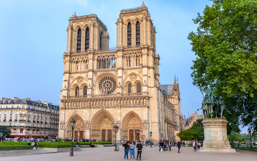 Notre Dame Cathedral facade with nearby statue during Paris walking tour.
