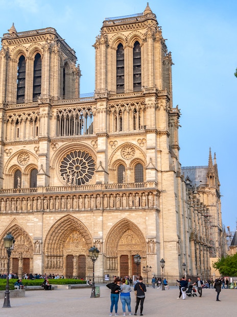 Notre Dame Cathedral facade with nearby statue during Paris walking tour.