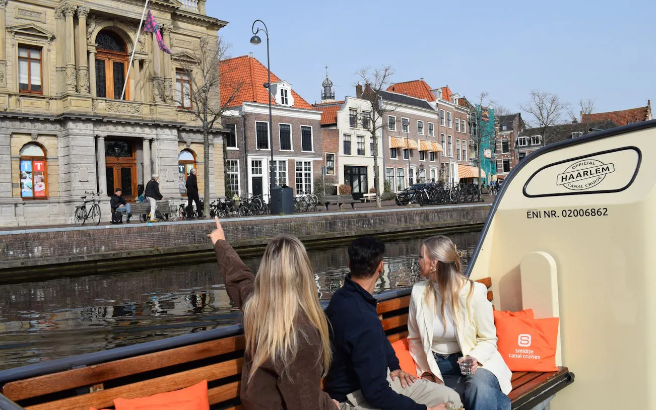 Haarlem canal cruise with tourists viewing historical buildings along the waterfront.