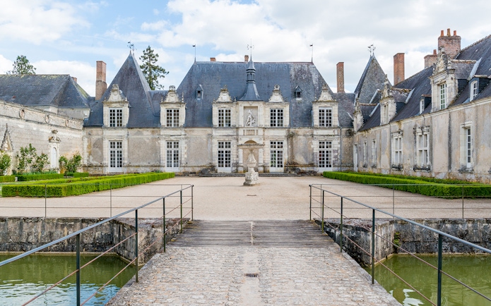 Château de Chambord entrance with bridge and manicured gardens on a sunny day.