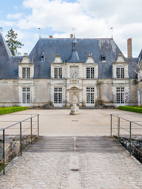 Château de Chambord entrance with bridge and manicured gardens on a sunny day.