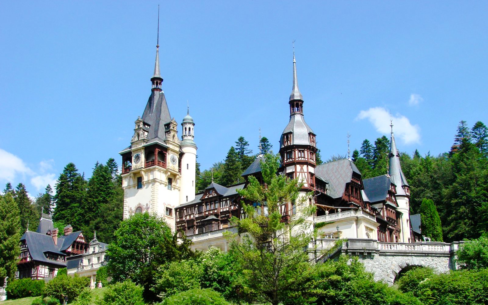 Peles Castle in Romania surrounded by lush green forest.