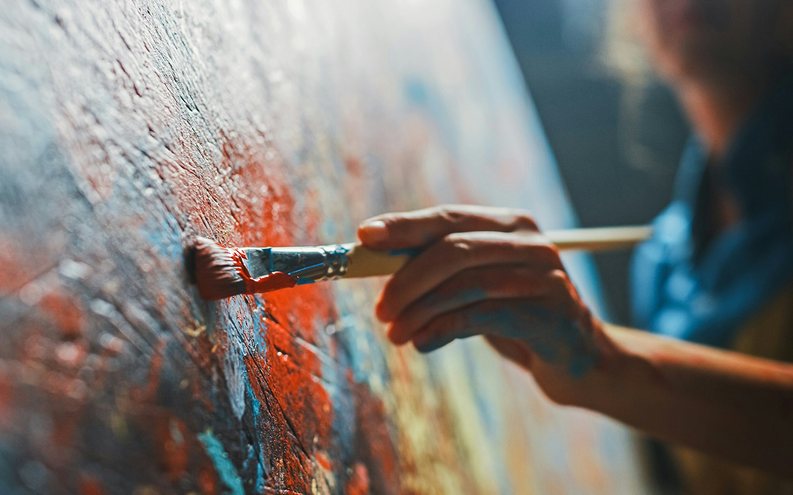 Artist painting vibrant colors on a canvas with a brush.