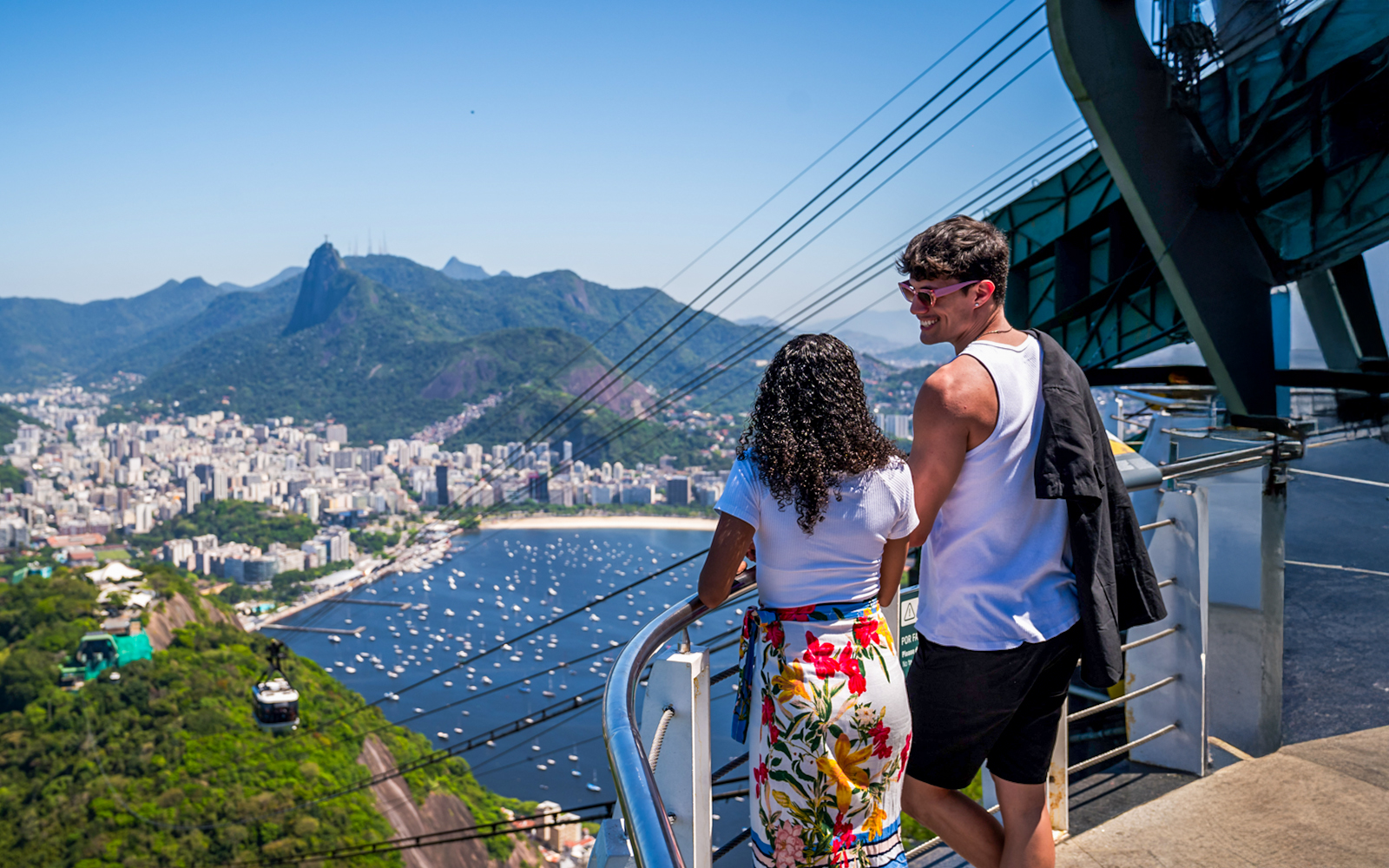 Cable cars descending from Sugarloaf Mountain with a view of Rio de Janeiro and Guanabara Bay.