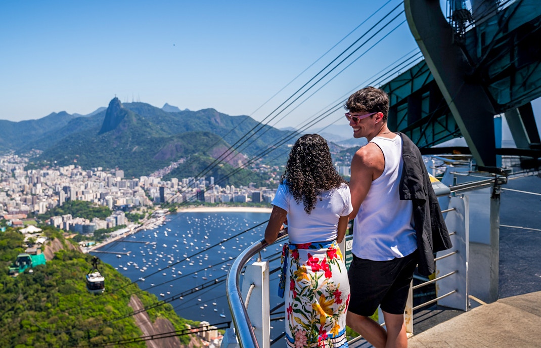 Cable cars ascending Sugarloaf Mountain, Rio de Janeiro, with cityscape and ocean views.