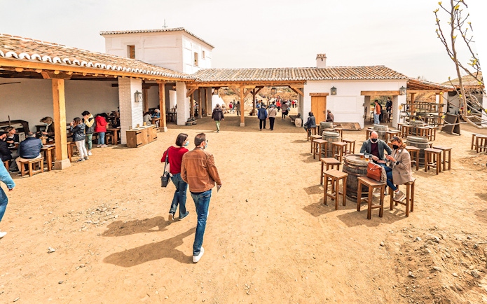 Visitors walking and dining in a rustic courtyard at Puy du Fou España Park.
