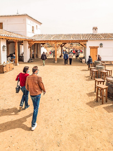 Visitors walking and dining in a rustic courtyard at Puy du Fou España Park.