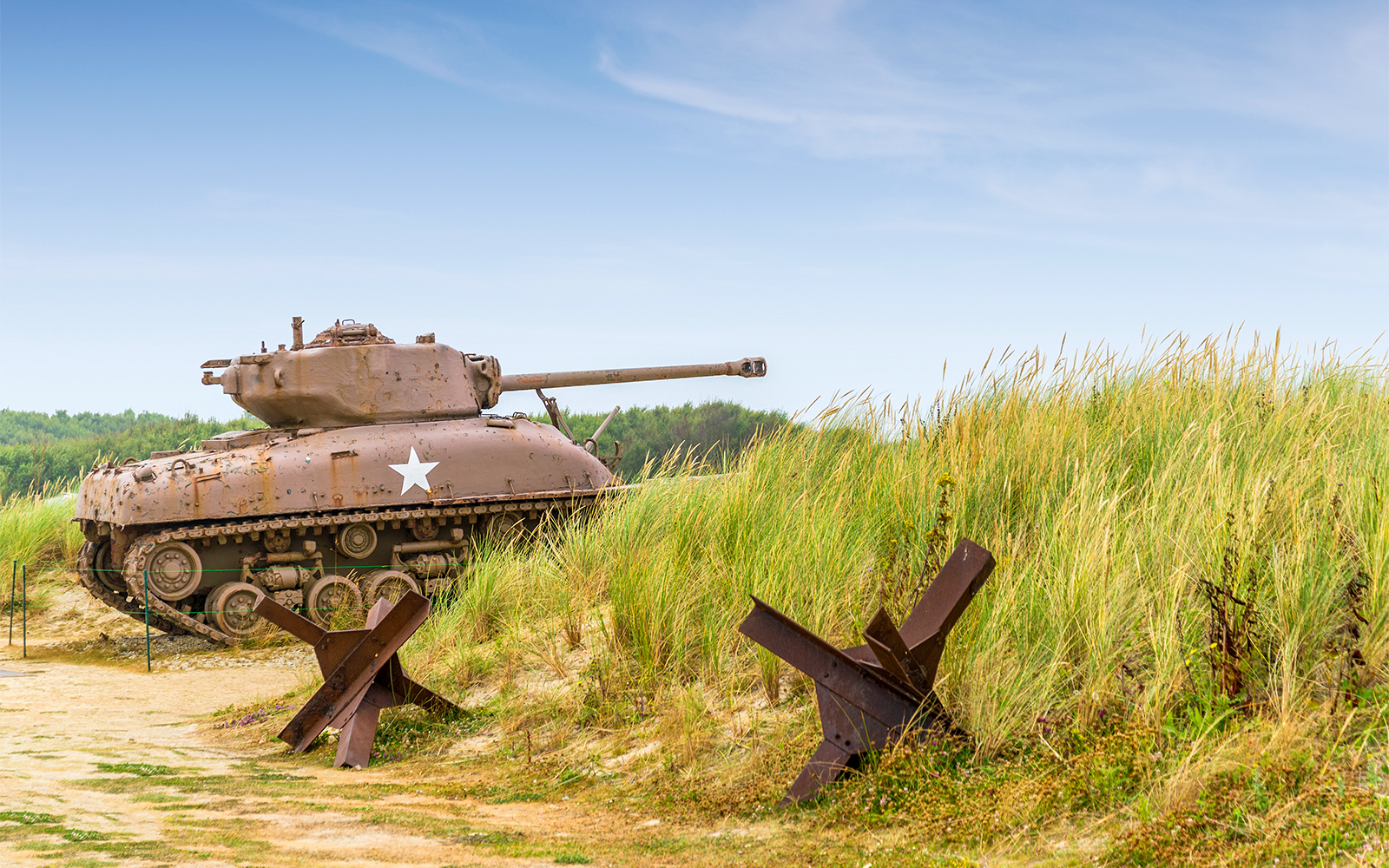 Normandy D-Day Tour visitors exploring Omaha Beach with historical bunkers in the background.