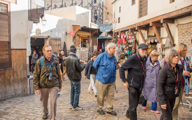 Tourists exploring the bustling souks in the Medina of Fes, Morocco.