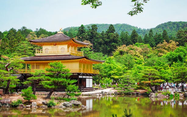 Kinkaku-ji Temple in Kyoto surrounded by lush greenery and reflecting pond.