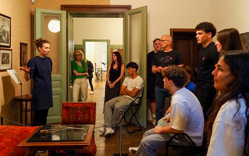 Guide leading tour inside Sigmund Freud Museum, Vienna, with visitors observing historical exhibits.