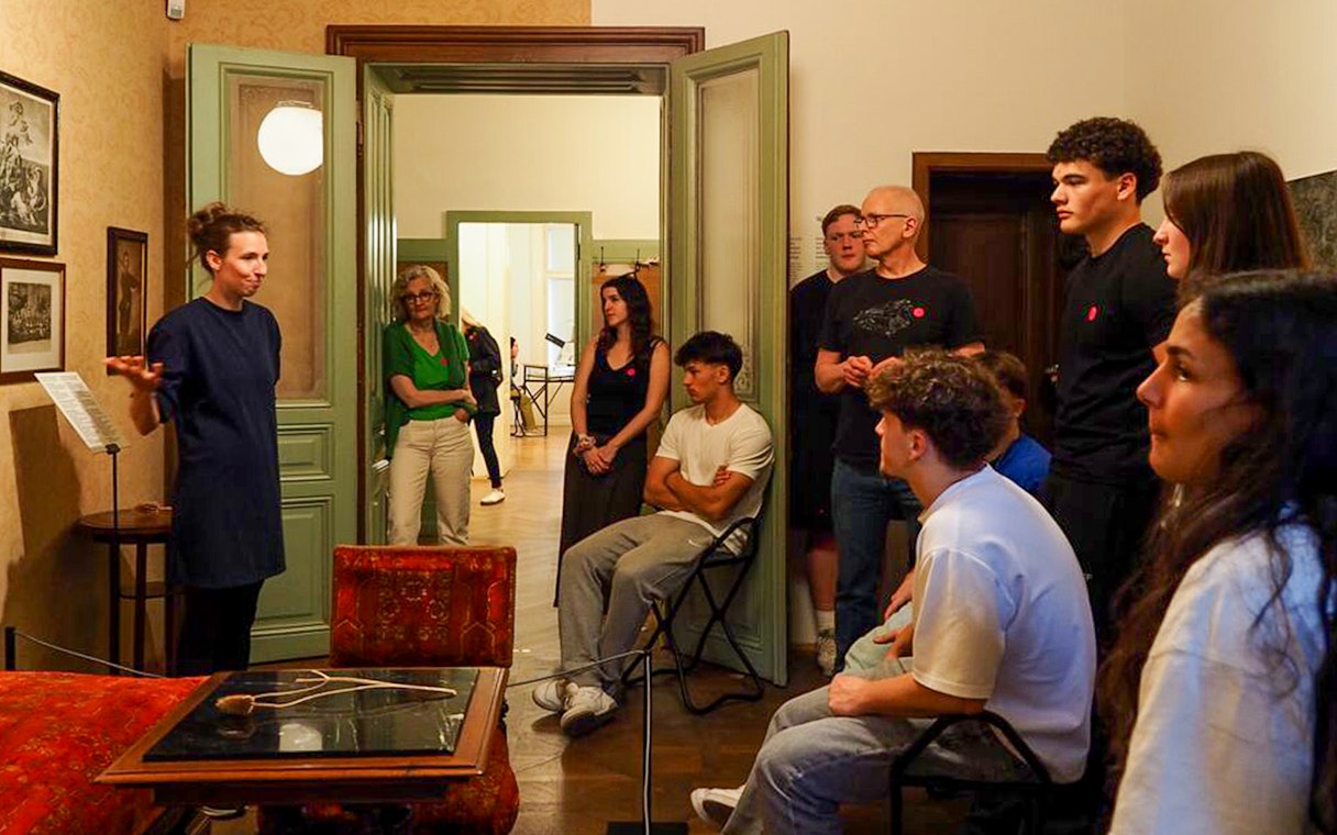 Guide leading tour inside Sigmund Freud Museum, Vienna, with visitors observing historical exhibits.