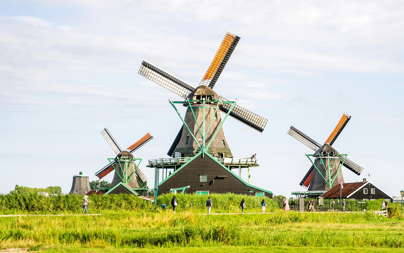 Windmills at Zaanse Schans, Netherlands, with visitors walking nearby.