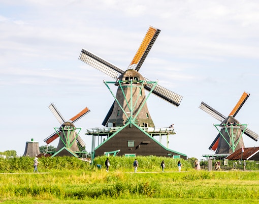 Windmills at Zaanse Schans, Netherlands, with visitors walking nearby.