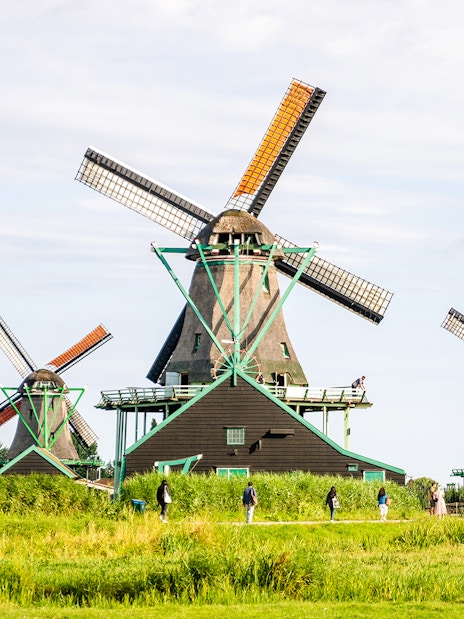 Windmills at Zaanse Schans, Netherlands, with visitors walking nearby.