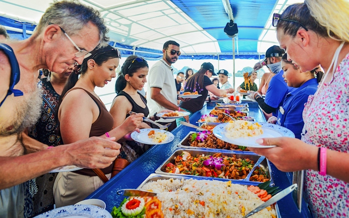 Tourists enjoying buffet lunch on a boat tour at Phang Nga Bay, Thailand.