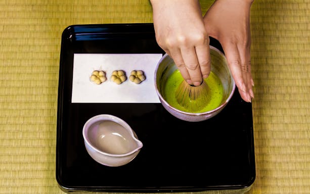 Matcha being whisked in a bowl during a traditional tea ceremony experience.