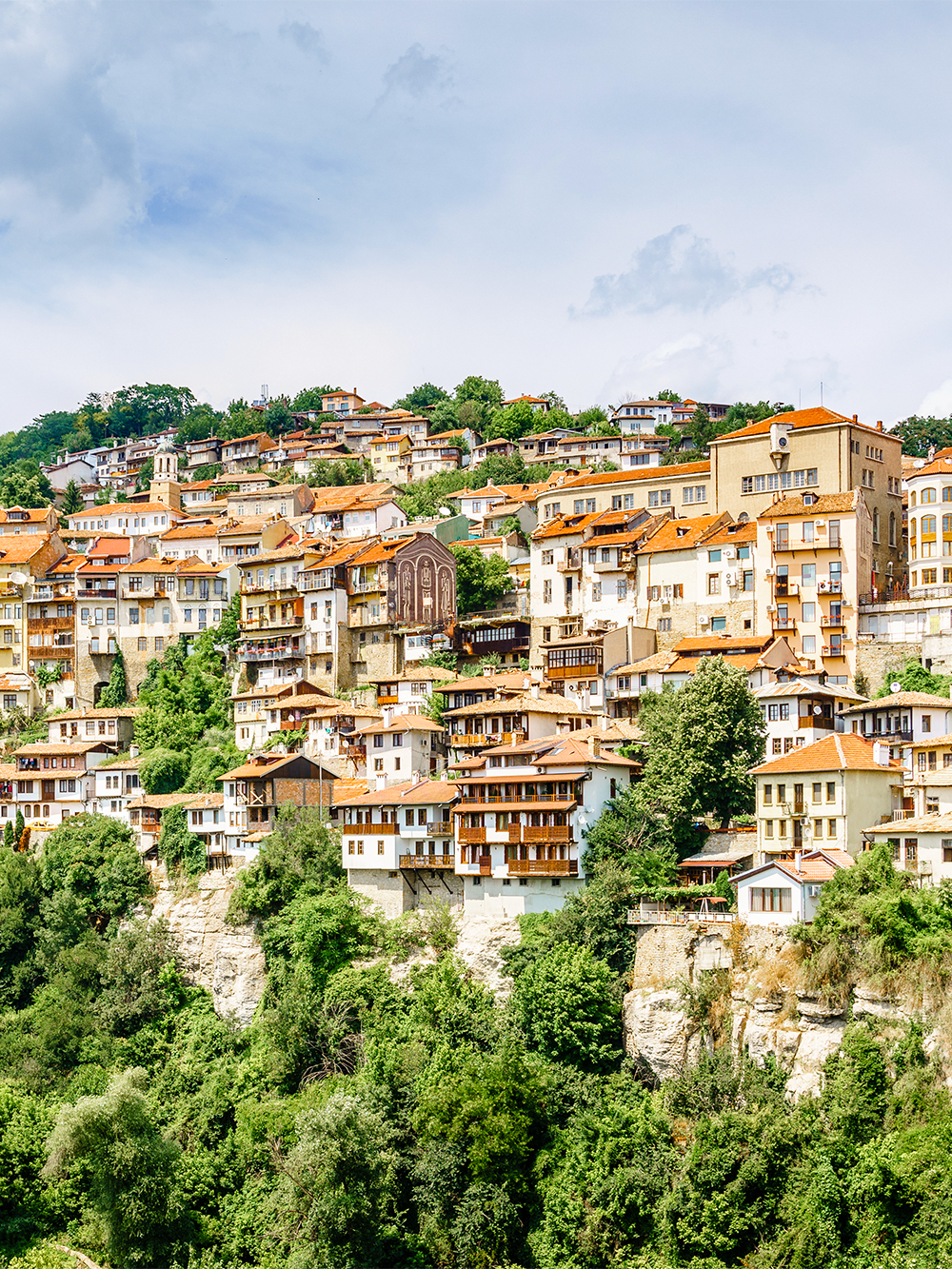 Veliko Tarnovo hillside with traditional houses and lush greenery.