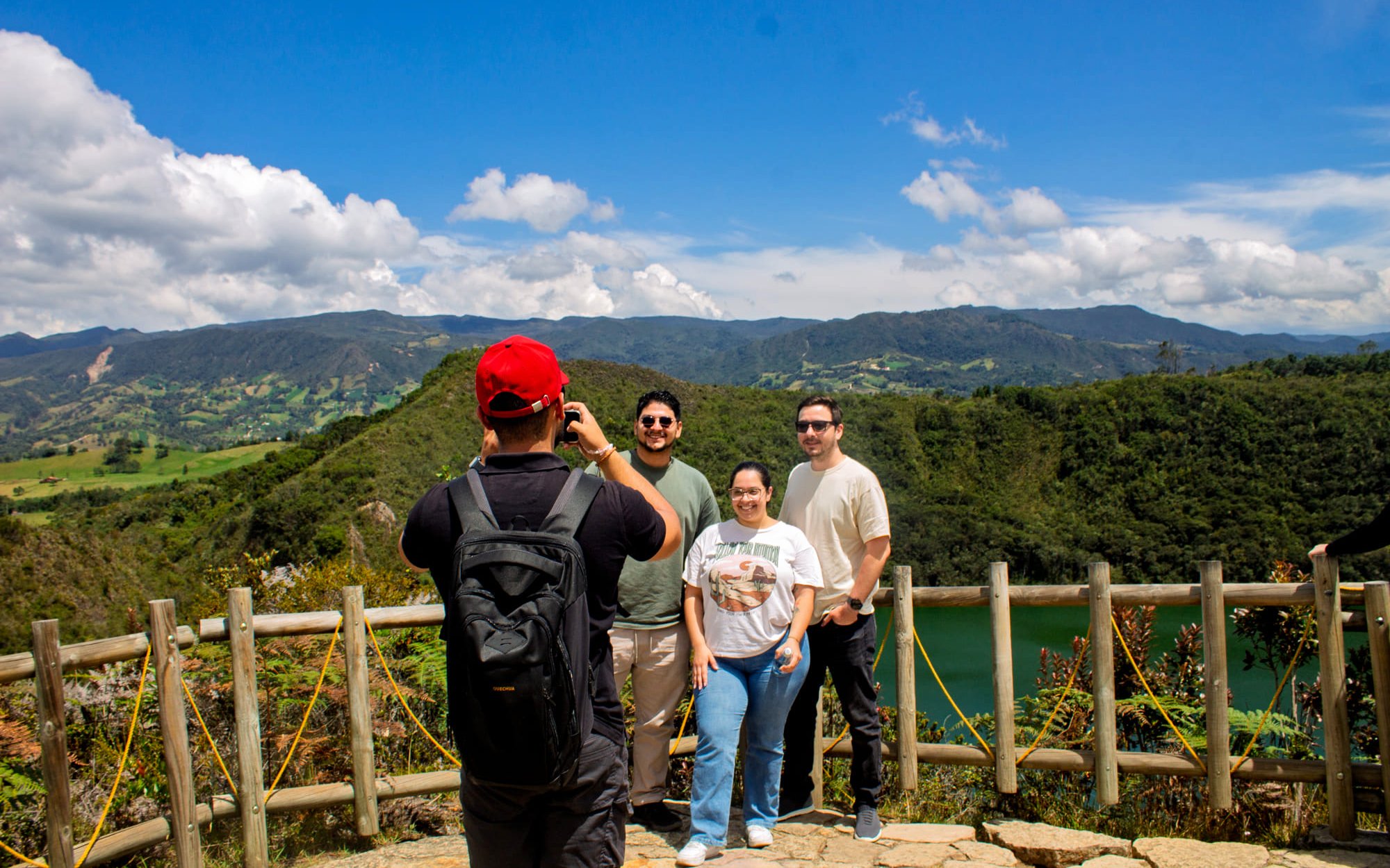 Visitors posing in front of Guatavita Lake, Colombia, with scenic mountain backdrop.