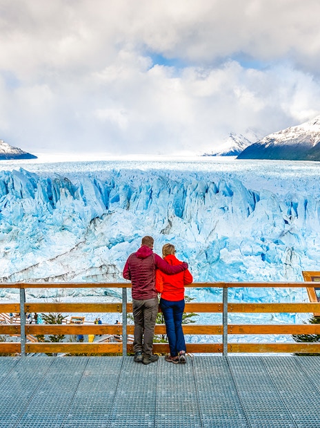 Couple admiring Perito Moreno Glacier from viewing deck in Argentina.