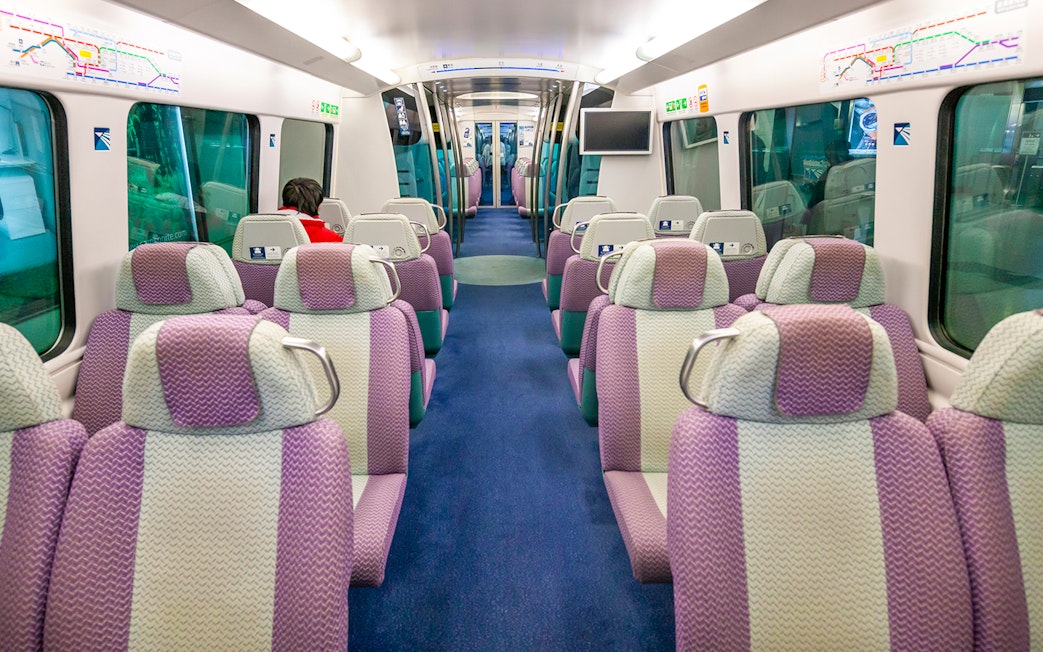 Interior of Hong Kong Airport Express train with empty seats and passenger.