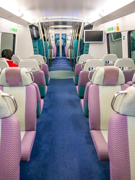 Interior of Hong Kong Airport Express train with empty seats and passenger.
