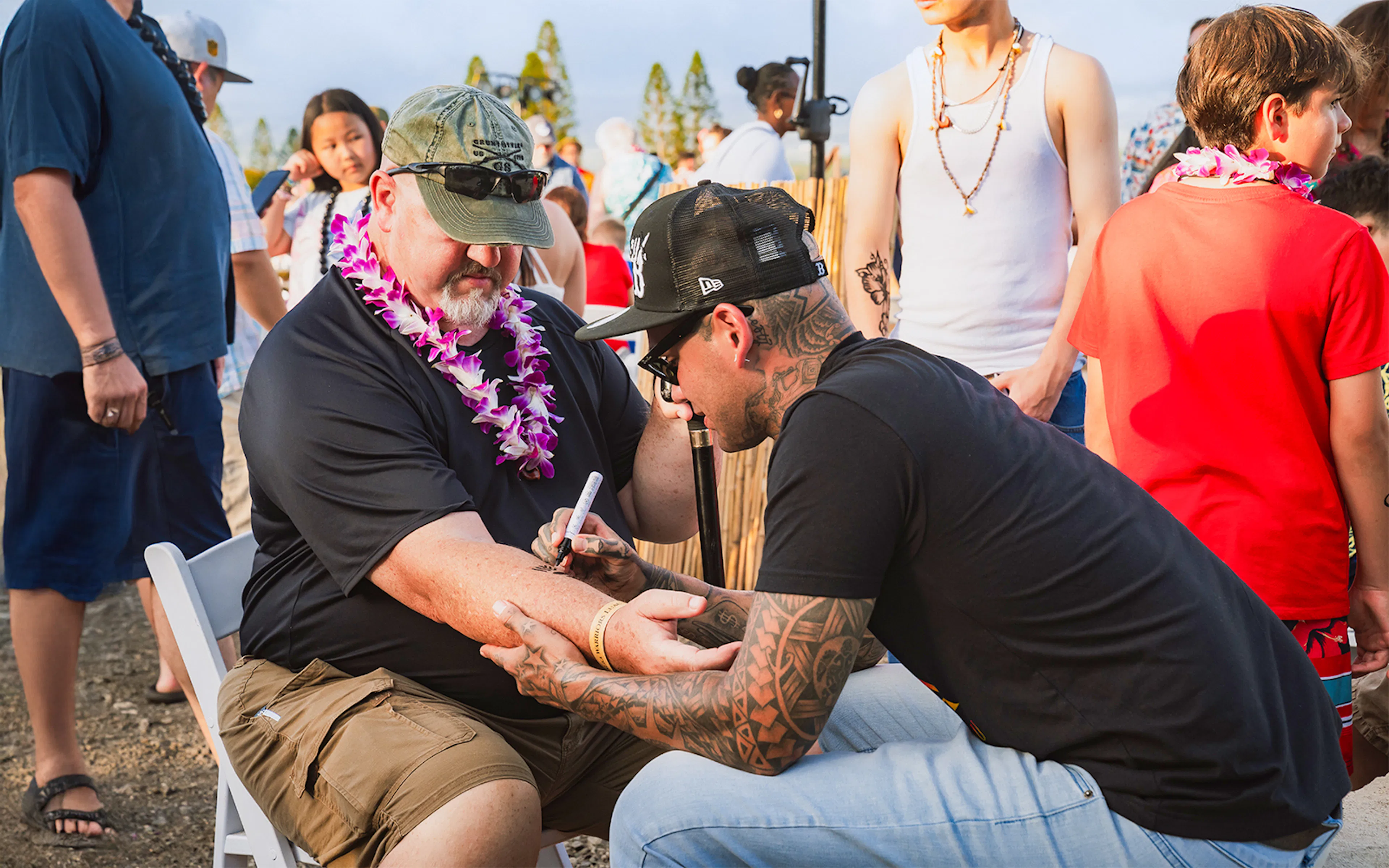 Man receiving traditional Hawaiian tattoo on arm at Mauka Warriors Luau, Hawaii.