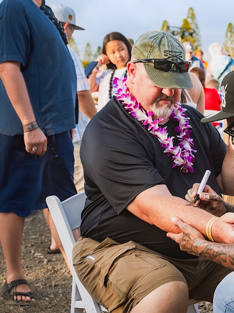 Man receiving traditional Hawaiian tattoo on arm at Mauka Warriors Luau.