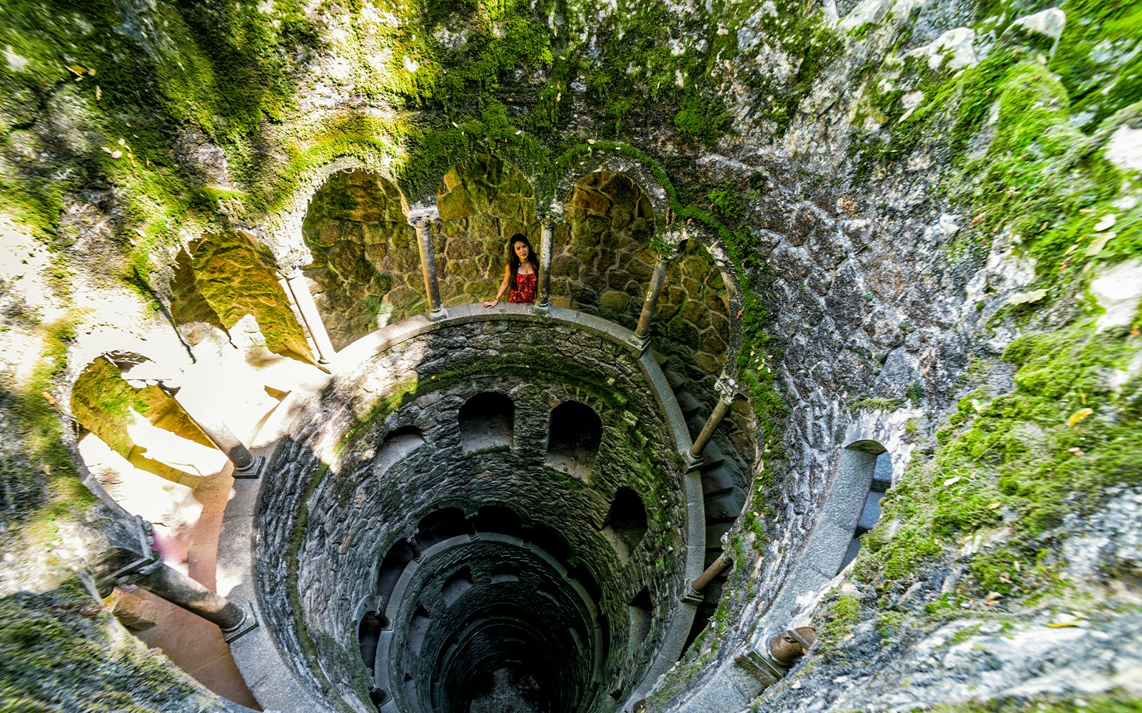 Quinta Da Regaleira initiation well with spiral staircase and stone arches in Sintra, Portugal.