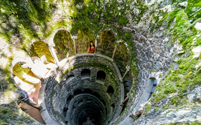 Quinta Da Regaleira initiation well with spiral staircase and stone arches in Sintra, Portugal.