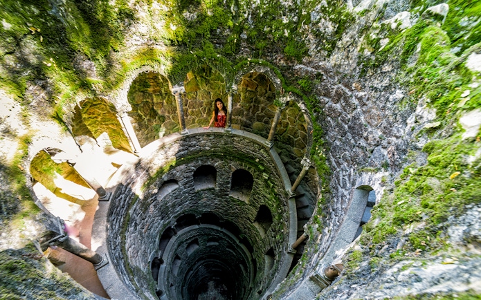 Quinta Da Regaleira initiation well with spiral staircase and stone arches in Sintra, Portugal.