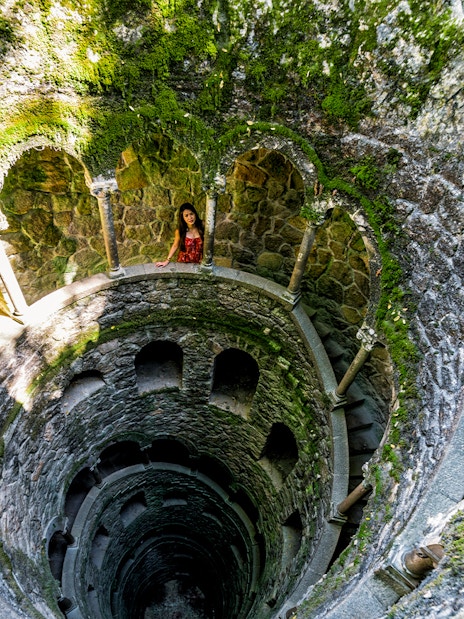 Quinta Da Regaleira initiation well with spiral staircase and stone arches in Sintra, Portugal.