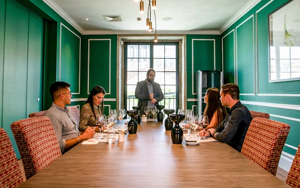 Wine tasting workshop with instructor and participants seated at a table with glasses.