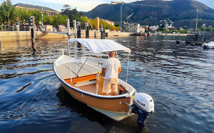 Boat rental on Lake Como with scenic mountain and waterfront views.