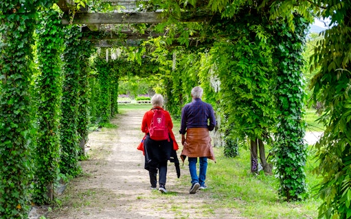 Visitors walking through a lush garden path at the Palace of Venaria.