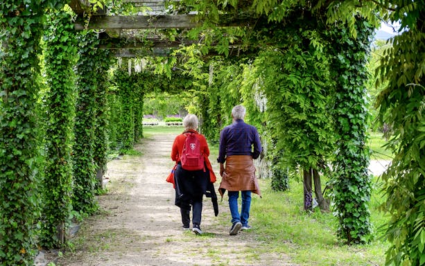Visitors walking through a lush garden path at the Palace of Venaria.