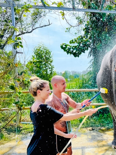 Couple showering an elephant at Phuket Elephant Care, Thailand.